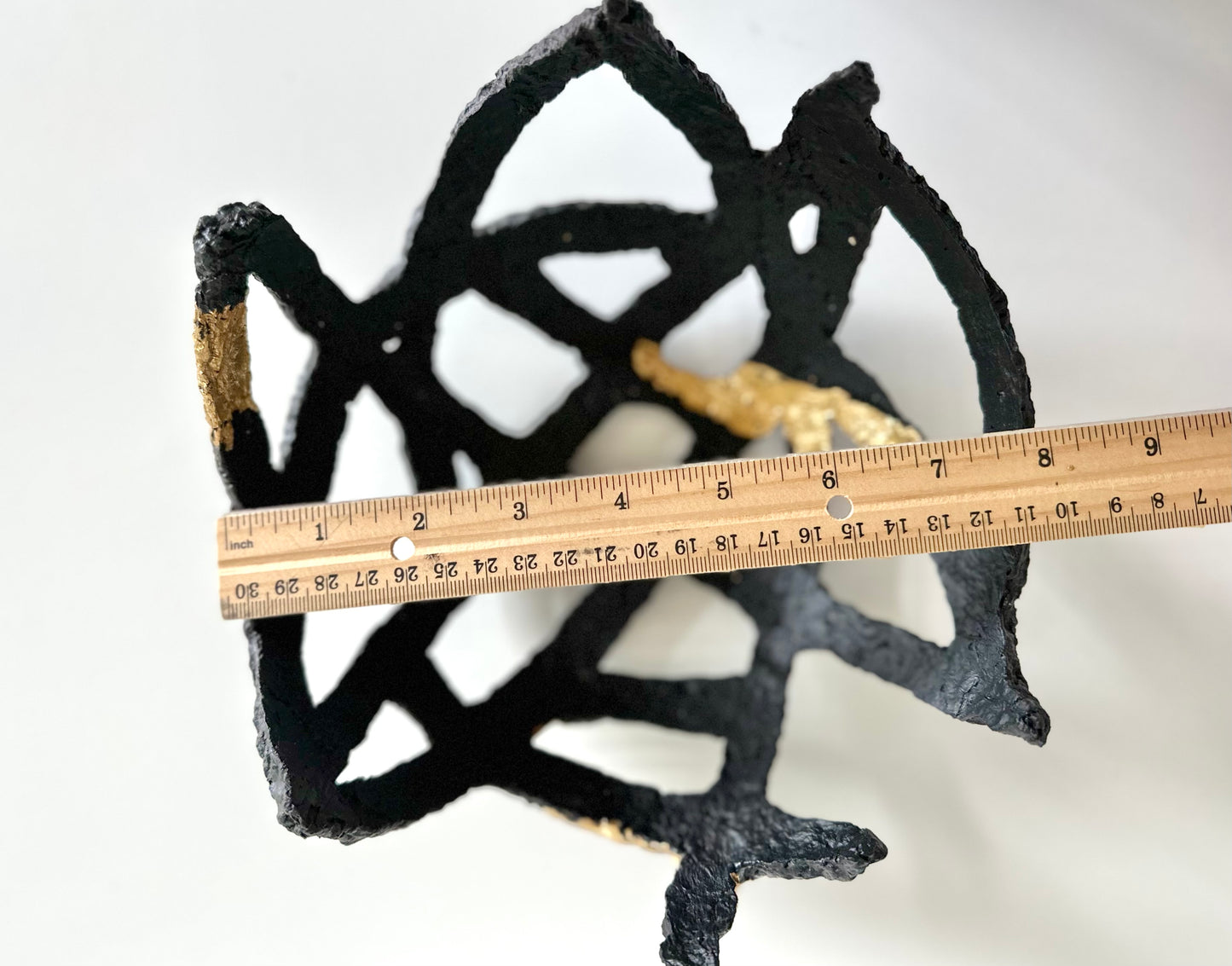 A small black and gold leaf, geometric-patterned paper mache decorative bowl on a white background. Measures about 8 inches wide. Handmade by artist Tam M Olson.