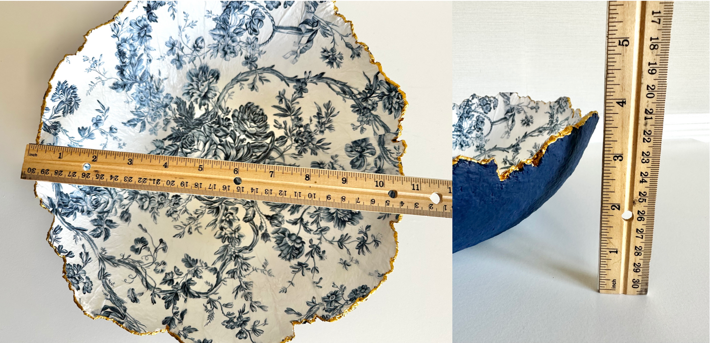 Split image of a large navy blue textured bowl with irregular gold edging and a floral toile pattern on the inside, displaying a width of 10.5 inches and a height of almost 4 inches. Handcrafted paper mache bowl by artist Tam M Olson.