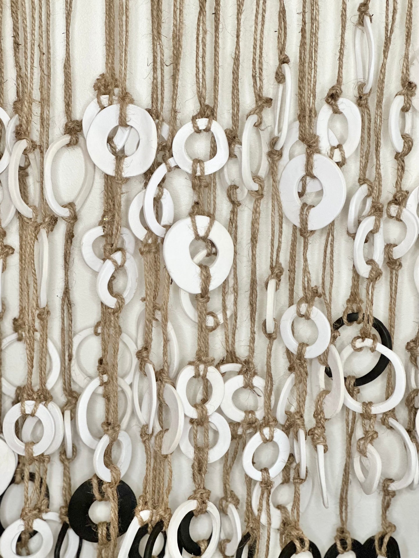 A wall hanging decor made of recycled driftwood with leather straps, jute string, and clay rings, sealed with paint and coffee grounds. Original artwork by artist Tam M Olson