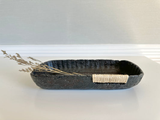 A small black decorative tray with a textured surface, made from paper mache, displayed in a home interior setting. Original art by artist Tam M Olson