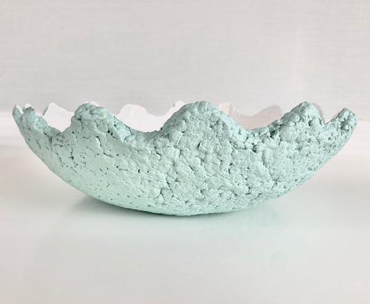 A pastel teal paper mache decorative bowl with wavy edges and a white interior. Handmade by artist Tam M Olson.