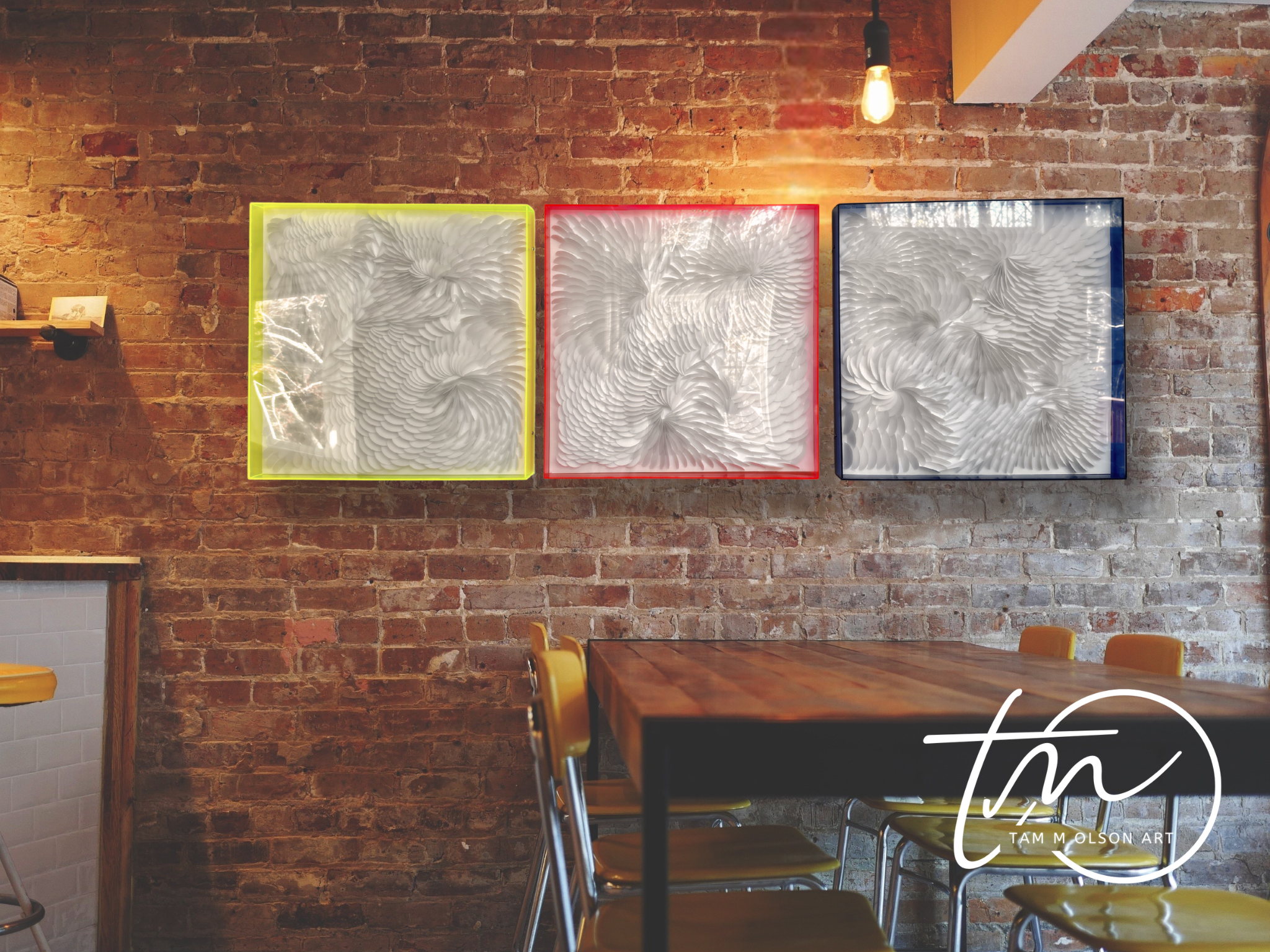 Restaurant dining area with a 3 pieces of dimensional art in acrylic shadow boxes on a brick wall and a table with chairs.