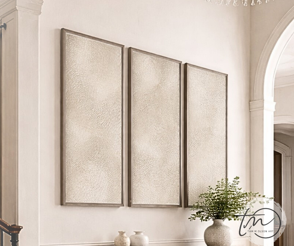 Three textured wall art pieces on a white wall with a plant and decorative items. Original Triptych wall art by commercial artist Tam M Olson