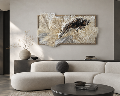Large framed wall art featuring textured beige, cream, gray, and black feather-like strands, displayed above a light beige sectional sofa in a modern living room setting. Original artwork by Artist Tam M Olson