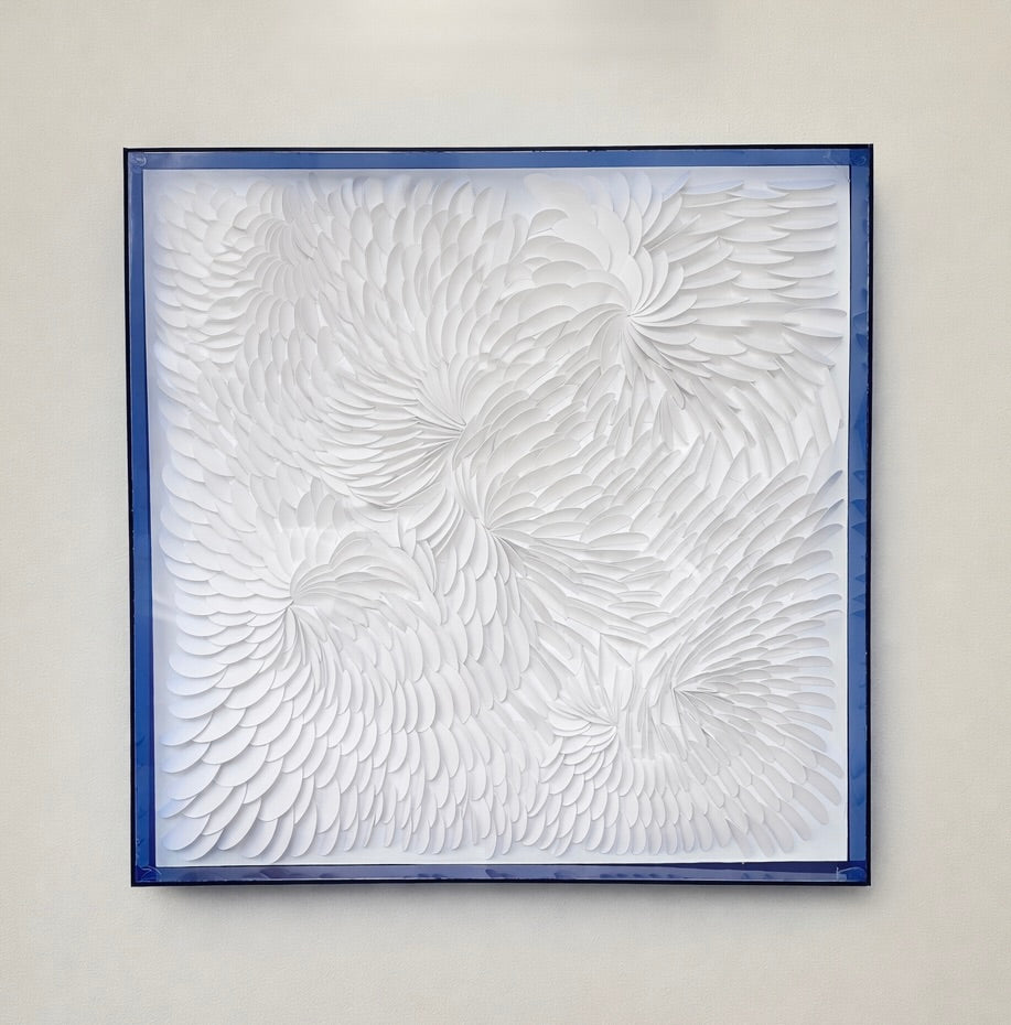 Abstract textured artwork in a blue acrylic frame on a beige wall by artist Tam M Olson