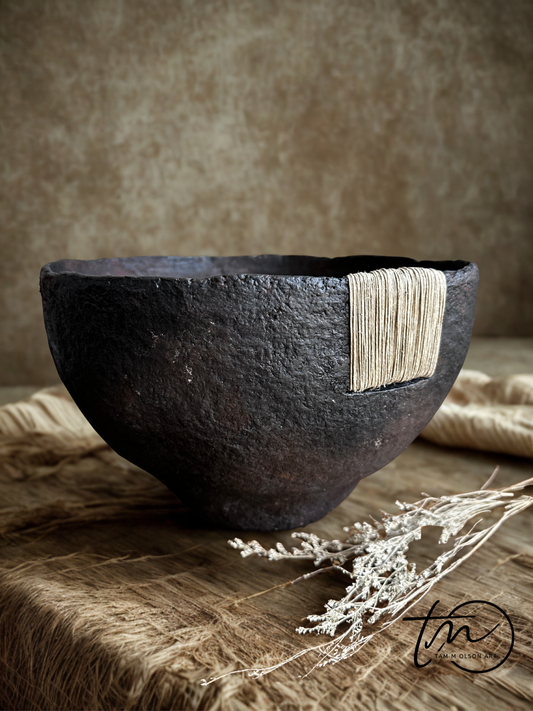 Tall black textural bowl with deep brown patina finish and jute twine accent sitting on a wooden surface. Handcrafted paper mache decorative bowl by Artist Tam M Olson.
