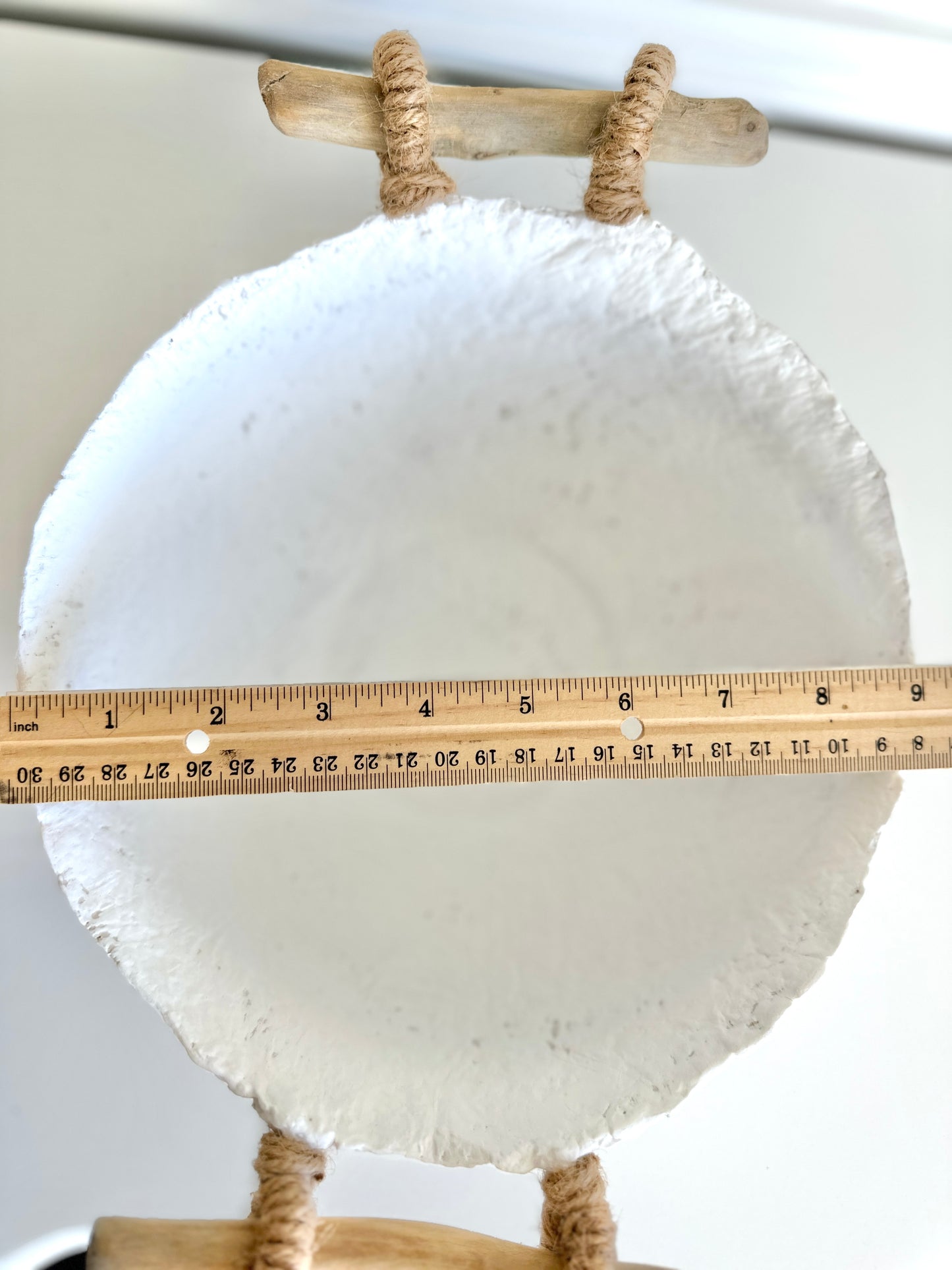 top down view of a handmade white paper mache bowl with driftwood and jute handles displaying bowl width without handles of 9 inches. Designed by Artist Tam M Olson.