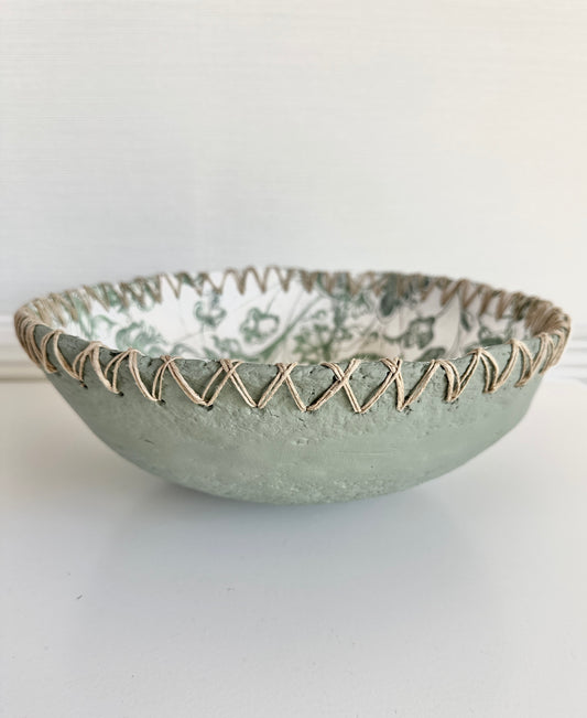Handmade muted green bowl with textured twine edge  and floral interior on a white background. Designed and created by Artist Tam M Olson