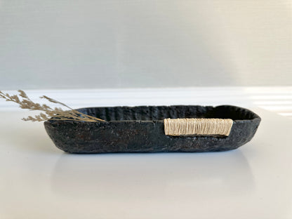 A small black decorative tray with a textured surface, made from paper mache, with jute string detail. Original art by artist Tam M Olson