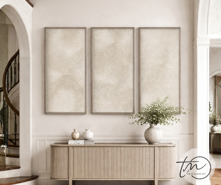 Three framed textured art pieces that flow from one to the next above a console table with decorative items in a room. Original abstract triptych art by Tam M Olson