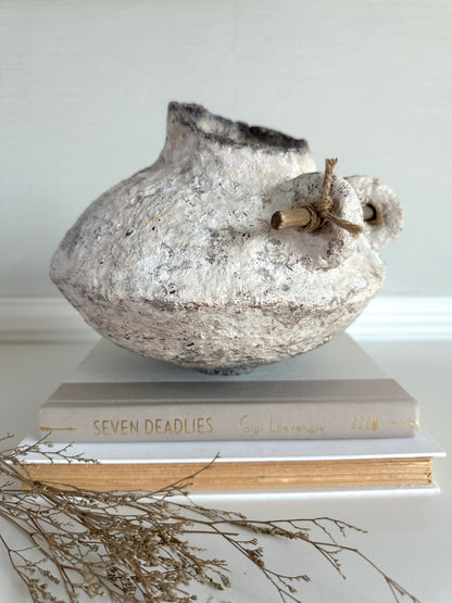 Decorative white rustic vase on top of books with a white background. Handmade by artist Tam M Olson