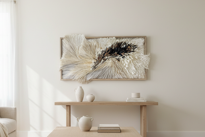 A rectangular wall-mounted art piece featuring layered, shaggy feather-like textures in cream, beige, gray, brown, and black, set within a light wood frame against a white background. Original art by Artist Tam M Olson