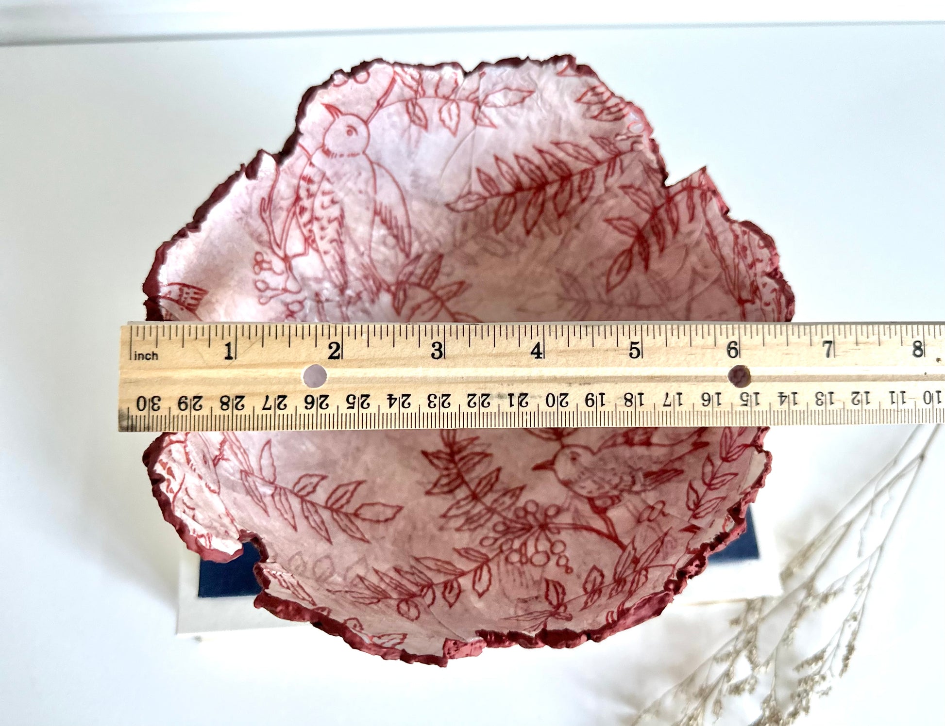 Top down view of a maroon eggshell decorative bowl with a rough torn edge, displaying an interior of birds and branches. Width shown as 6.5 inches. Handcrafted by artist Tam M Olson.