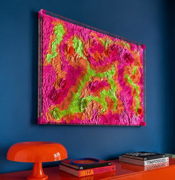Colorful textured artwork on a blue wall with an orange table and books below. Original dimensional abstract art by Tam M Olson