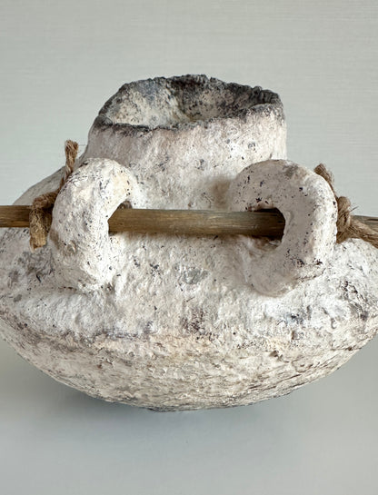 Decorative organic pitcher with a central wooden rod on a light gray background handmade by artist Tam M Olson